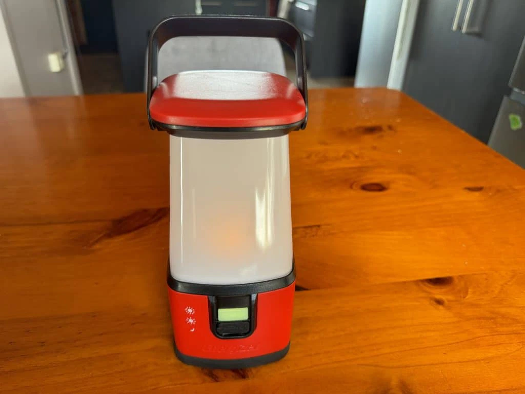 A red and black lantern sitting on a wooden table.